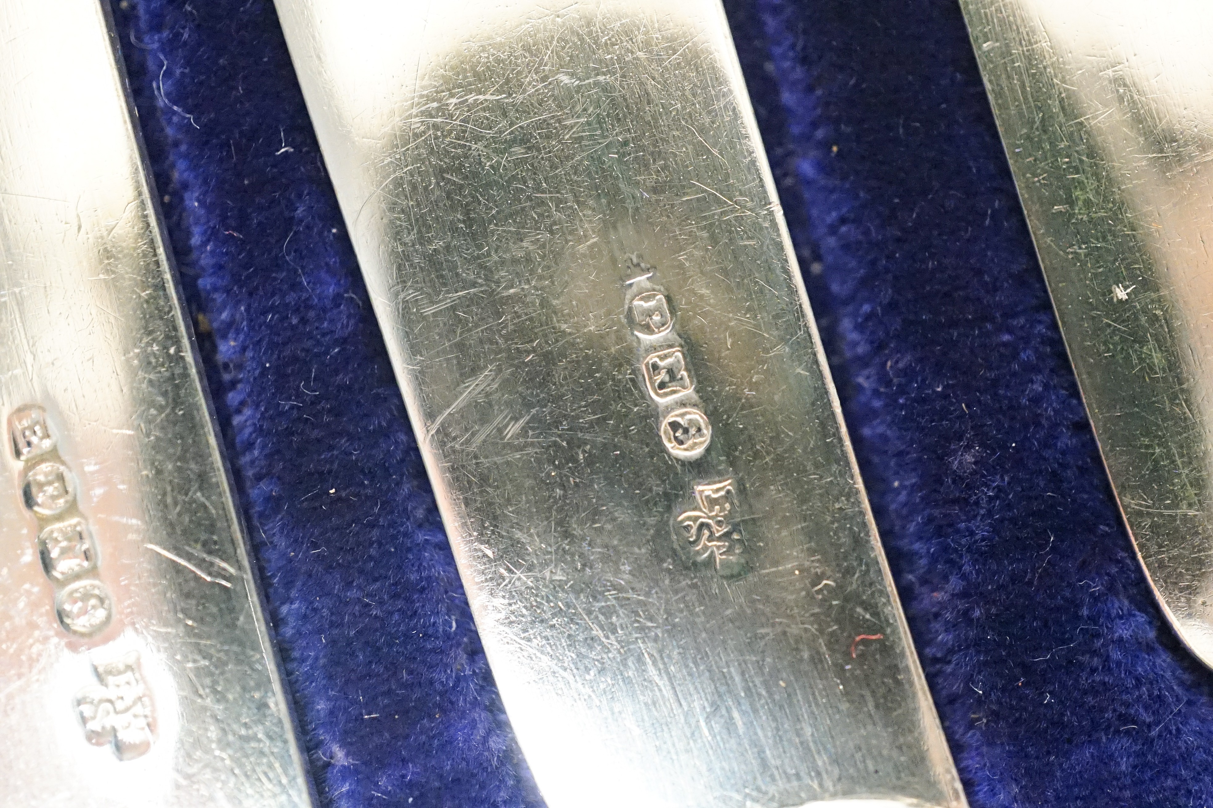 A cased set of twelve reeded silver pistol handled steel dessert knives and a cased set of six silver teaspoons.